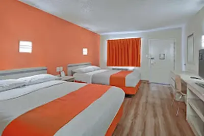 a room with three beds and an orange wall at Value Extended Stay in Maple Shade