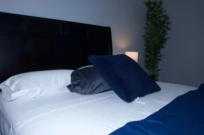 a bed with a blue pillow on top of it at New York private room 29 in West New York
