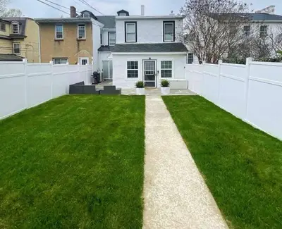 a backyard with a white fence and green grass at Retreat with Parking Sleeps 6 in Phoenixville