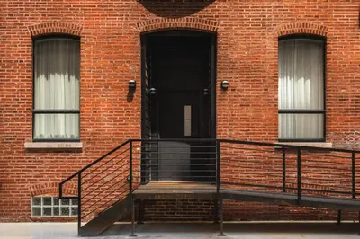 a brick building with a staircase leading to a black door at Stunning Artisan Loft Chic & Modern - The Botanist in Philadelphia