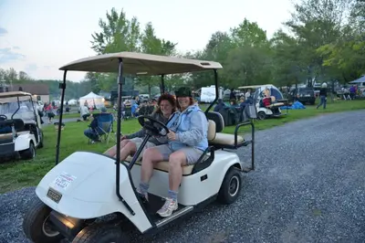 a man and woman sitting on a golf cart at Spring Gulch Lakefront Park Model 5 in Mount Airy
