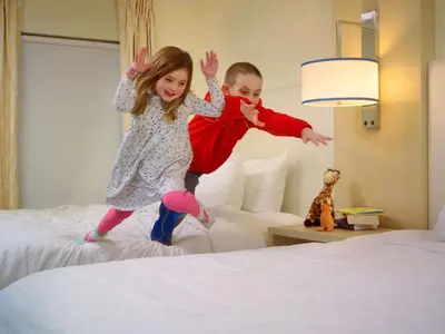 a boy and a girl jumping on a bed at Sonesta ES Suites Somerset in Somerset