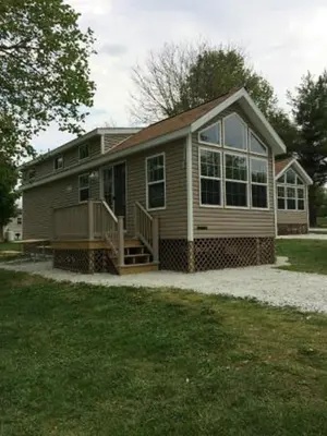 a small house with a porch and a large window at Circle M Camping Resort Loft Park Model in Wabank