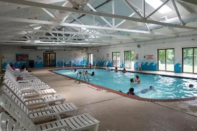 a large swimming pool with chairs and people in it at Circle M Camping Resort Loft Park Model in Wabank