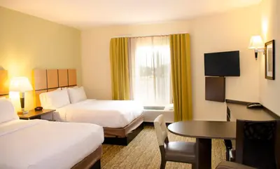 a hotel room with two beds and a table at Candlewood Suites - Lancaster West by IHG in Lancaster