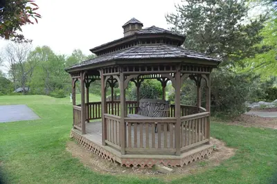 a wooden gazebo with two benches in the grass at Appalachian Camping Resort Cottage 1 in Shartlesville