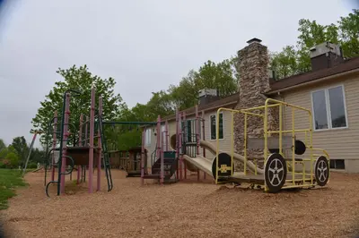 a playground in front of a house at Appalachian Camping Resort Log Home 6 in Shartlesville