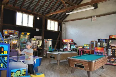 a man standing in a game room with pool tables at Robin Hill Camping Resort Premium Cottage 1 in Lenhartsville