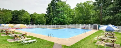 a large swimming pool with tables and chairs around it at Sun Valley Campground Cottage 6 in Maple Grove Park