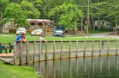 a woman and child looking over a wooden bridge over water at Sun Valley Campground Cottage 6 in Maple Grove Park
