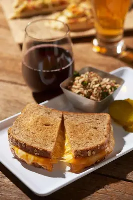 a sandwich on a plate with a salad and a glass of wine at Hyatt Place Bethlehem-Downtown in Bethlehem