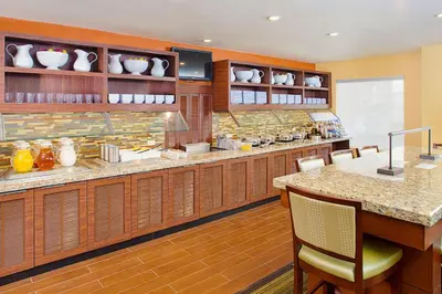 a kitchen with wooden cabinets and a counter with chairs at Hyatt House Mount Laurel in Mount Laurel