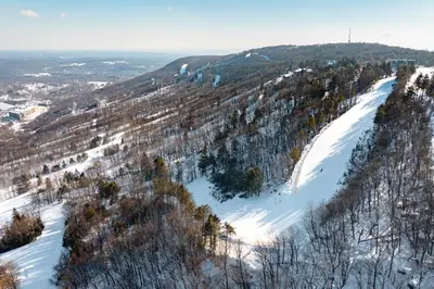 a snow covered hill with trees and a ski slope at Northridge 482 in Tannersville