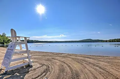 a lifeguard chair sitting on a beach near a body of water at Deck and Fire Pit Pocono Lake Home Near Skiing! in Pocono Lake