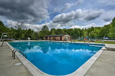 a large blue swimming pool in front of a house at Creekside Arrowhead Lake House with Dock and Canoe! in Pocono Lake