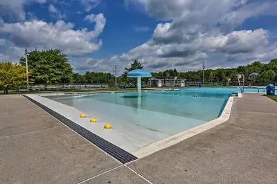 a large swimming pool with a blue umbrella in it at Pocono Lake House Near Skiing and Kalahari Resort! in Pocono Lake