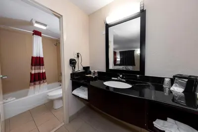 a bathroom with a sink and a toilet and a mirror at HomeTowne Studios by Red Roof Bordentown - McGuire AFB in Bordentown