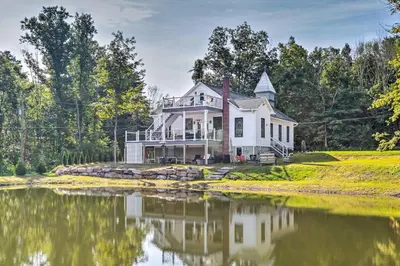 a white house with a pond in front of it at Unwind Fireside! Poconos Cottage 12 Mi to Slopes in Brodheadsville