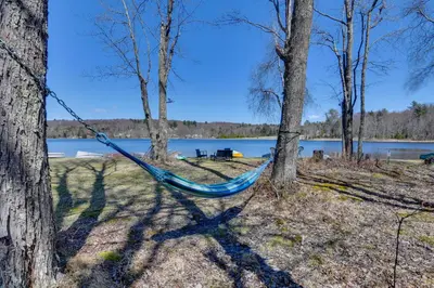 a blue hammock hanging between two trees near a lake at Shared Fire Pit and Kayaks Catskills Lake Retreat! in Ellenville