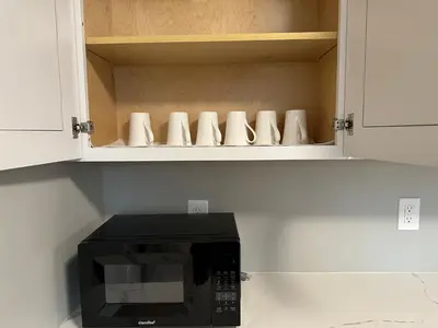 a black microwave in a kitchen with white cabinets at M2 Comfortable Room near Rutgers U, hospitals in New Brunswick