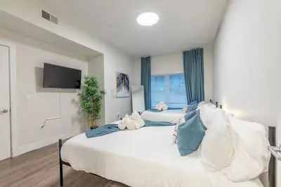 a large white bedroom with two beds and a tv at Blue Breakaway with Free Parking and Sleeps 9, Book 7 days, Get 20 Percent OFF in East Orange