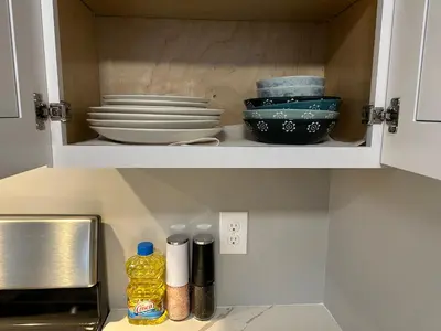 a kitchen cabinet with plates and bowls in it at J2 Pleasant Queens Size room near St. Peter's hospital & New Brunswick Downtown in New Brunswick
