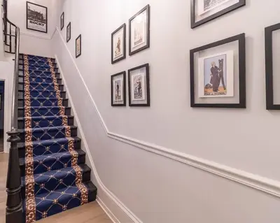 a hallway with a staircase with framed pictures on the wall at Thena Hotel - Large Studio in Philadelphia