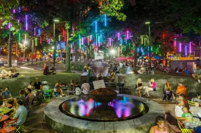 people sitting around a fountain in a park at night at Thena Hotel - Cozy Studio in Philadelphia