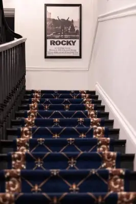 a staircase with a blue carpet and a picture on the wall at Thena Hotel - Cozy Studio in Philadelphia