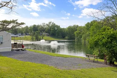 a park with a bench next to a lake at Cozy Cabin Within Campground in Mifflinburg