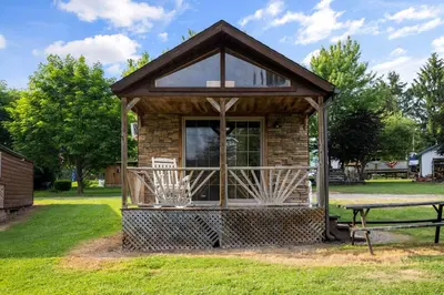 a small cabin with a table in a park at Deluxe Cabin Within Campground in Mifflinburg