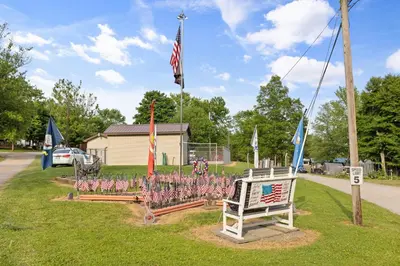 a park with flags and a bench with a sign at Deluxe Cabin Within Campground in Mifflinburg