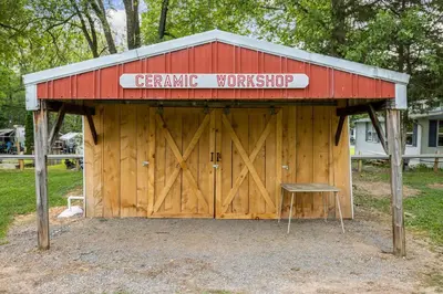 a barn with a sign on it with a bench in front at Cozy Cabin2 Within Campground in Mifflinburg