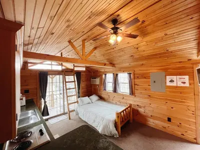 a bedroom with a bed in a wooden cabin at Deluxe Cabin7 Within Campground in Mifflinburg