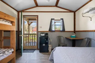 a room with a bed and a refrigerator in a room at Cozy Cabin3 Within Campground in Mifflinburg